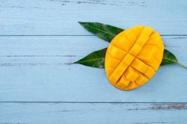Taze mango, koyu ahşap masa arka plan üzerinde yeşil yaprakları ile güzel doğranmış meyve. Tropikal meyve tasarım konsepti. Düz yatıyordu. Üst te. Kopyalama alanı