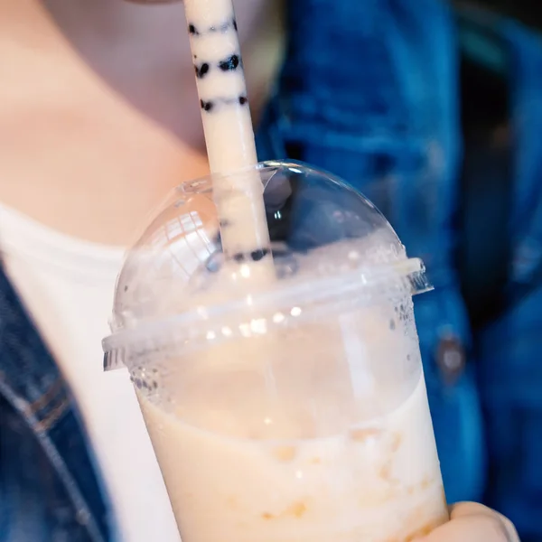 Chica joven en chaqueta de mezclilla está bebiendo azúcar morena con sabor a tapioca perla té de leche de burbuja con paja de vidrio en el mercado nocturno de Taiwán, de cerca, bokeh — Foto de Stock