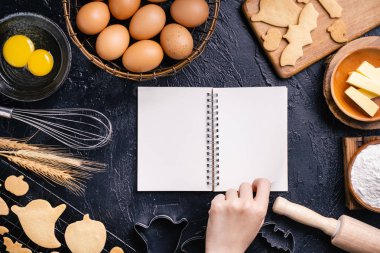 Kadın pişirme malzemeleri ile Halloween çerezleri yapma yemek kitabı tarifi okuyor, pişirme sınıfı tasarım kavramı, üst görünüm, düz yatıyordu, havai.