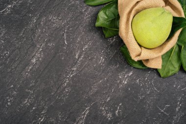 Taze pomelo, pummelo, greyfurt, koyu siyah kayrak arka plan üzerinde yaprak ile bambu sepeti nde shaddock. Mevsim meyvesi konsepti. Üst te. Düz yatıyordu.