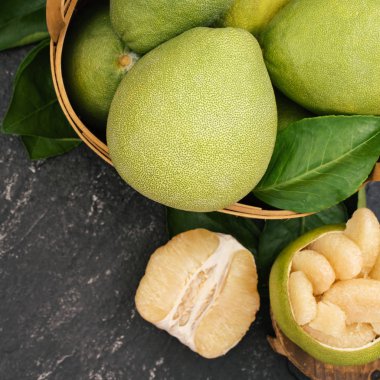 Taze pomelo, pummelo, greyfurt, koyu siyah kayrak arka plan üzerinde yaprak ile bambu sepeti nde shaddock. Mevsim meyvesi konsepti. Üst te. Düz yatıyordu.