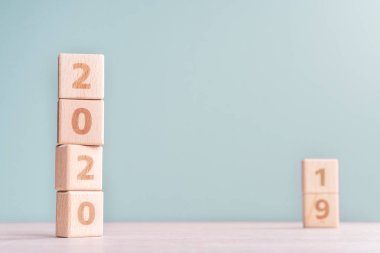 Soyut 2020 & 2019 Yeni yıl geri sayım tasarım konsepti - ahşap bloklar ahşap masa ve düşük doygunluk yeşil arka plan küpler, yakın çekim, kopyalama alanı.