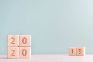 Soyut 2020 & 2019 Yeni yıl geri sayım tasarım konsepti - ahşap bloklar ahşap masa ve düşük doygunluk yeşil arka plan küpler, yakın çekim, kopyalama alanı.