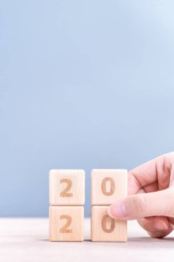 Soyut 2020 & 2019 Yeni yıl geri sayım tasarım konsepti - ahşap masa ve mavi arka plan üzerinde ahşap blokküpler tutan kadın, yakın çekim, kopyalama alanı.