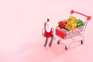 Noel alışveriş konsepti, Noel Baba oyuncak ve hediye kutusu soluk pembe arka plan, boş kopya alanı, yakın izole ile mini kırmızı dükkan arabası arabası