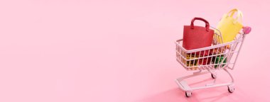 Yıllık satış alışveriş sezonu konsepti - mini kırmızı dükkan arabası arabası soluk pembe arka plan, boş kopya alanı, yakın izole kağıt torba hediye dolu