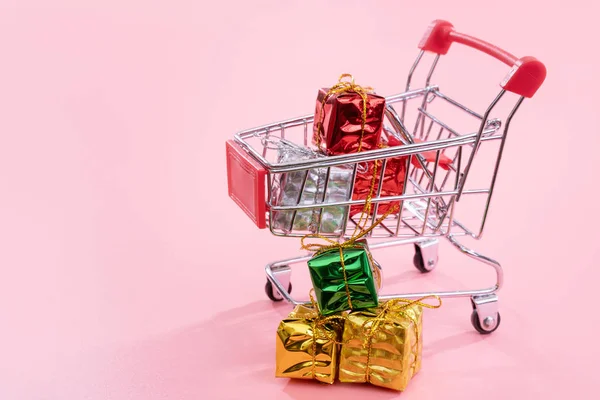 Annual sale, Christmas shopping season concept - mini red shop cart trolley full of gift box isolated on pale pink background, copy space, close up — Stock Photo, Image