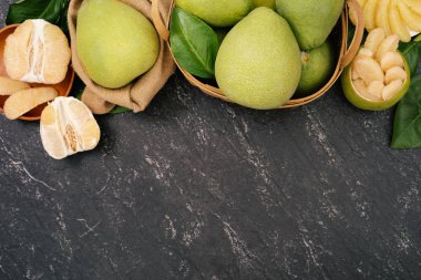 Taze soyulmuş pomelo, pummelo, greyfurt, bambu sepetinde koyu arka planda Shaddock. Sonbahar mevsimlik meyveler, üst manzara, düz yatış, masa üstü çekimi.