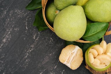 Taze soyulmuş pomelo, pummelo, greyfurt, bambu sepetinde koyu arka planda Shaddock. Sonbahar mevsimlik meyveler, üst manzara, düz yatış, masa üstü çekimi.