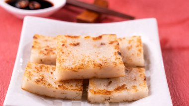 Çin 'in yeni yıl yemeği konsepti, enfes turp keki, kırmızı arka planda soya sosu olan yerel bir restoran mutfağı, kapat, uzayı kopyala.
