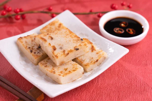 Çin 'in yeni yıl yemeği konsepti, enfes turp keki, kırmızı arka planda soya sosu olan yerel bir restoran mutfağı, kapat, uzayı kopyala.