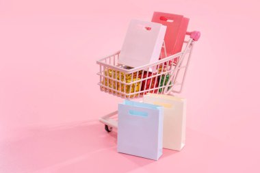 Yıllık satış alışveriş sezonu konsepti - mini kırmızı dükkan arabası arabası soluk pembe arka plan, boş kopya alanı, yakın izole kağıt torba hediye dolu