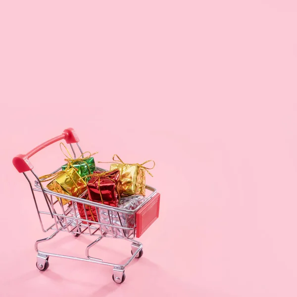 Roční prodej, koncept vánoční obchodní sezóny-Mini červený vozík plný dárkové krabice izolovaný na světle růžovém pozadí, místo kopírování, uzavření — Stock fotografie