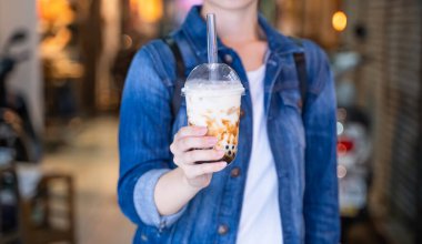 Genç bir kadın, Tayvan 'ın gece pazarında elinde kahverengi şeker aromalı muhallebi sütlü çay içiyor. Yaklaş, Bokeh.