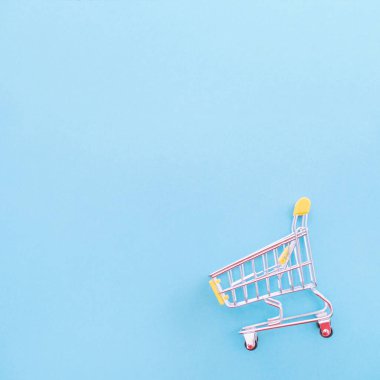 Soyut tasarım unsuru, yıllık satış, alışveriş sezonu konsepti, pastel mavi arka planda renkli kağıt çantalı mini sarı sepet, üst manzara, düz yatış