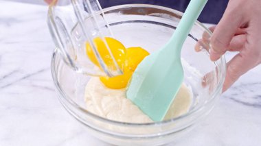 Yumurta sarısını kek hamuruna karıştırarak yeşil kauçuk spatula karıştırma aleti ile karıştırarak pürüzsüz olana kadar karıştırır ve karıştırır, kapayın, yaşam tarzınızı