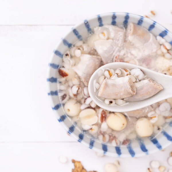 Вкусный суп из четырех тоников, тайваньская традиционная еда с травами, свиной кишечник на белом деревянном столе, крупный план, плоская кладка, вид сверху
