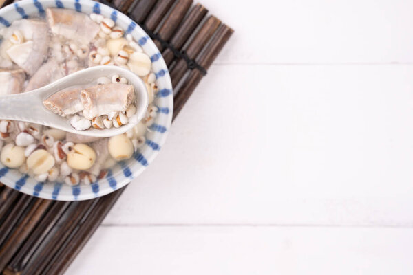 Вкусный суп из четырех тоников, тайваньская традиционная еда с травами, свиной кишечник на белом деревянном столе, крупный план, плоская кладка, вид сверху
