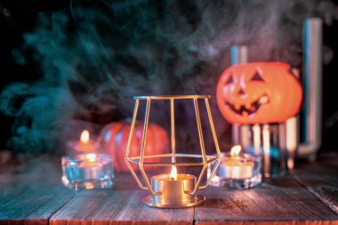 Kabak Cadılar Bayramı tatil konsept tasarımı, mum, koyu ahşap bir masa etrafında yeşil tonlu duman ile ürkütücü süslemeleri, çekim yakın.