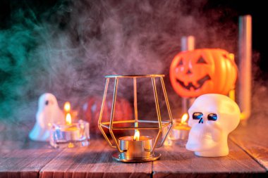 Kabak Cadılar Bayramı tatil konsept tasarımı, mum, koyu ahşap bir masa etrafında yeşil tonlu duman ile ürkütücü süslemeleri, çekim yakın.