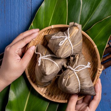 Pirinç köftesi, zongzi - Ejderha Teknesi Festivali 'nin yeşil yapraklı arka planında geleneksel Çin yemeği, Duanwu Festivali, üst manzara, düz dizayn konsepti.