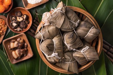 Pirinç köftesi, zongzi - Ejderha Teknesi Festivali 'nin yeşil yapraklı arka planında geleneksel Çin yemeği, Duanwu Festivali, üst manzara, düz dizayn konsepti.