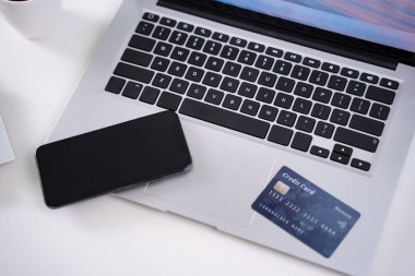 Ofis çevrimiçi ödeme, alışveriş, kredi kartı konsepti olan elektronik ödeme, dükkan arabası olan beyaz masa arkaplanı olan dizüstü bilgisayar, kapat..