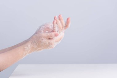 El yıkama. Asyalı genç bir kadın ellerini yıkamak için sıvı sabun kullanıyor, koruyucu pandemik koronavirüs konsepti gri beyaz arka planda izole edilmiş, kapatın..