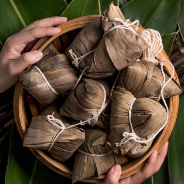 Pirinç köftesi, zongzi - Ejderha Teknesi Festivali 'nin yeşil yapraklı arka planında geleneksel Çin yemeği, Duanwu Festivali, üst manzara, düz dizayn konsepti.