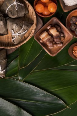 Pirinç köftesi, zongzi - Ejderha Teknesi Festivali 'nin yeşil yapraklı arka planında geleneksel Çin yemeği, Duanwu Festivali, üst manzara, düz dizayn konsepti.