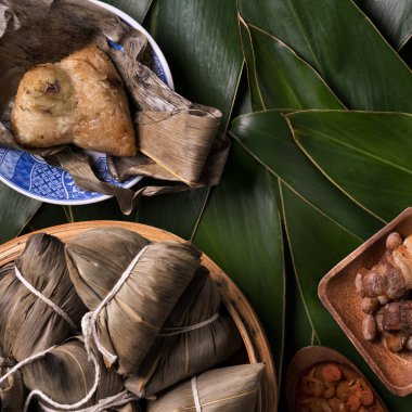 Pirinç köftesi, zongzi - Ejderha Teknesi Festivali 'nin yeşil yapraklı arka planında geleneksel Çin yemeği, Duanwu Festivali, üst manzara, düz dizayn konsepti.
