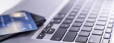 Ofis çevrimiçi ödeme, alışveriş, kredi kartı konsepti olan elektronik ödeme, dükkan arabası olan beyaz masa arkaplanı olan dizüstü bilgisayar, kapat..