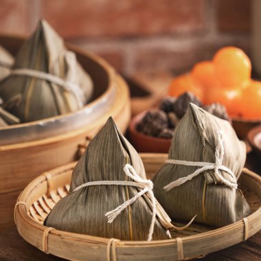 Rice dumpling - Chinese zongzi food in a steamer on wooden table with red brick wall, window background at home for Dragon Boat Festival concept, close up.