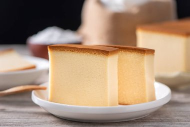 Castella - Lezzetli Japon dilimlenmiş sünger keki beyaz tabakta, ahşap masa üzerinde, yakın plan, sağlıklı beslenme, kopyalama alanı tasarımı.