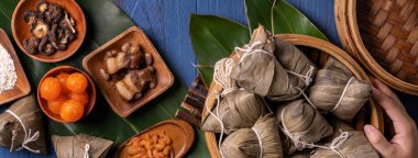 Zongzi - Ejderha Teknesi Festivali konsepti Pirinç köftesi, Duanwu Festivali için mavi ahşap arka planda geleneksel Çin yemeği, üst manzara, düz dizayn konsepti.
