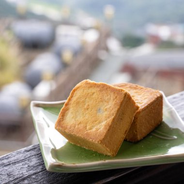 Delicious pineapple pastry in a plate for afternoon tea on wooden railing of a teahouse in Taiwan with beautiful landscape in background, close up.