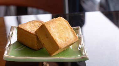 Delicious pineapple pastry in a plate for afternoon tea on wooden railing of a teahouse in Taiwan with beautiful landscape in background, close up.