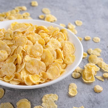 Mısır gevreği kasesi şekerleri gri çimento arka planda süt, yakın plan, taze ve sağlıklı kahvaltı tasarımı konsepti.