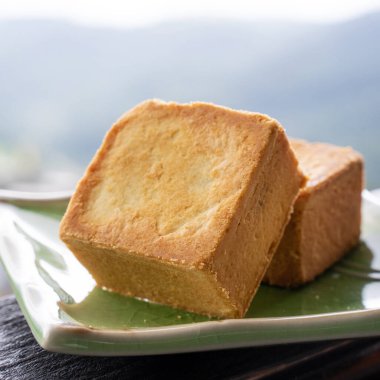 Delicious pineapple pastry in a plate for afternoon tea on wooden railing of a teahouse in Taiwan with beautiful landscape in background, close up.
