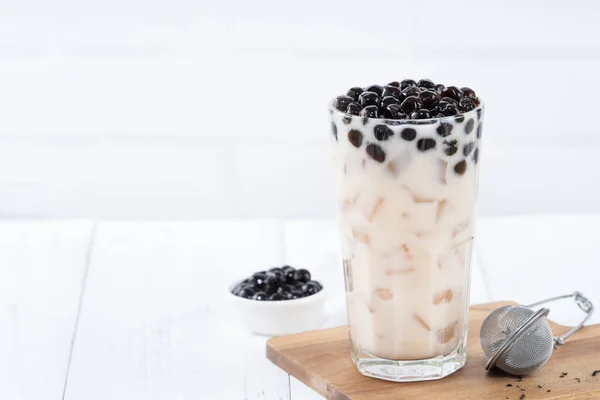 Bubble milk tea with tapioca pearl topping, famous Taiwanese drink on white wooden table background in drinking glass, close up, copy space