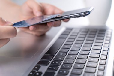 Ofis çevrimiçi ödeme, alışveriş, kredi kartı konsepti olan elektronik ödeme, dükkan arabası olan beyaz masa arkaplanı olan dizüstü bilgisayar, kapat..