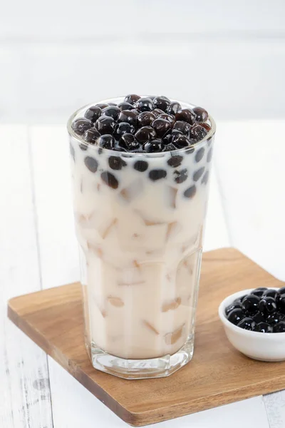 Bubble milk tea with tapioca pearl topping, famous Taiwanese drink on white wooden table background in drinking glass, close up, copy space