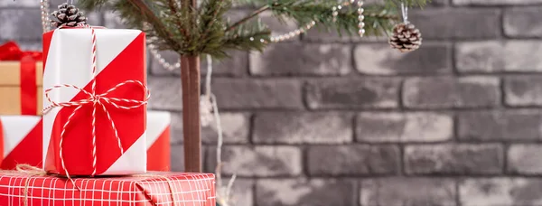 黒レンガの壁 お祝いのデザインコンセプトと自宅で美しい赤と白の贈り物を包んだクリスマスツリーを飾る クローズアップ — ストック写真