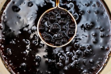 Pişirme, kaynamış kahverengi şeker aromalı tapyoka inci topları, balonlu çayın içeriği, yemek ve içecek hazırlama, yakın plan, yemek kitabı adımları tasarımı konsepti.