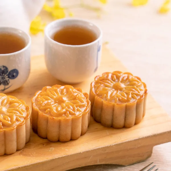 Tasty baked egg yolk pastry moon cake for Mid-Autumn Festival on bright wooden table background. Chinese festive food concept, close up, copy space.