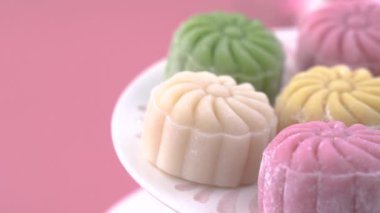 Renkli kar tenli ay pastası, tatlı karlı ay pastası, pastel soluk pembe arka planda geleneksel sonbahar festivali için lezzetli tatlı, yakın plan, yaşam tarzı.