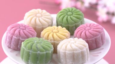 Renkli kar tenli ay pastası, tatlı karlı ay pastası, pastel soluk pembe arka planda geleneksel sonbahar festivali için lezzetli tatlı, yakın plan, yaşam tarzı.