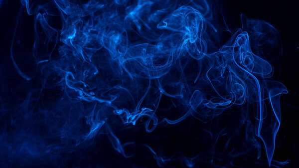 Conceptual image of blue color smoke isolated on dark black background, Halloween design element concept.