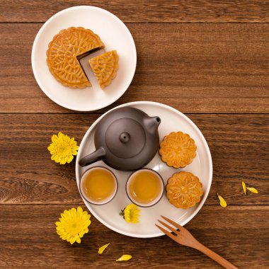 Sonbahar ortası festivali için ay pastası, koyu ahşap bir arka plan masasının üzerindeki tabakta nefis taze ay pastası, üst manzara, düz dizayn konsepti..