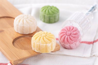 Colorful snow skin moon cake, sweet snowy mooncake, traditional savory dessert for Mid-Autumn Festival on bright wooden background, close up, lifestyle. clipart